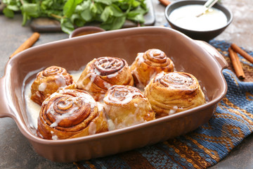 Baking tray with tasty cinnamon buns on table