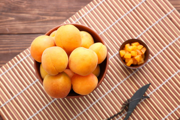 Bowl with tasty sweet apricots on wooden background