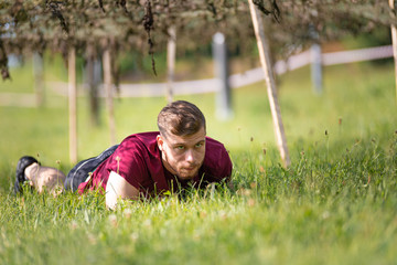 Young man crawling during obstacle course training in the boot camp