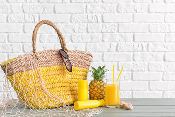 Beach bag and accessories on table against white brick wall