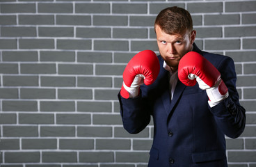 Businessman in boxing gloves against brick wall