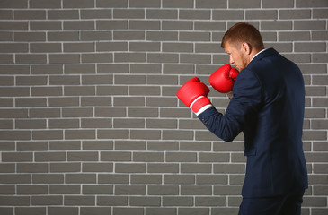 Businessman in boxing gloves against brick wall