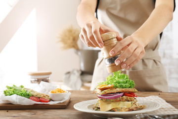 Woman adding spices to tasty squash waffles on plate