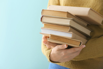 Woman with books on color background, closeup