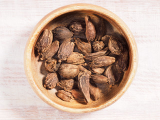 Black cardamom (Amomum subulatum) on a brown wooden cup on a wooden background
