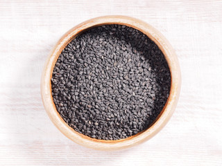 Black sesame (Sesamum) in brown wooden cup on wooden background