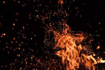 Fototapeta na wymiar Burning sparks flying. Beautiful flames. Fiery orange glowing flying away particles on black background.