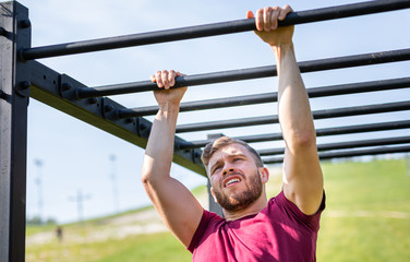 Runner overcome obstacle by hands during extreme race in the boot camp