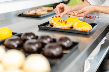 Pastry chef putting cranberries on top of little tartelettes