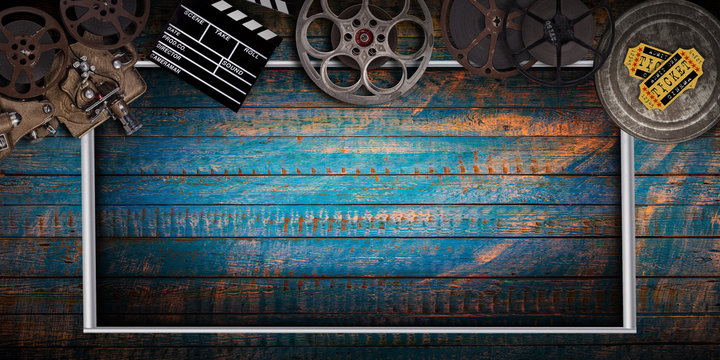 Cinema concept of vintage film reels, clapperboard and projector on old wooden background.