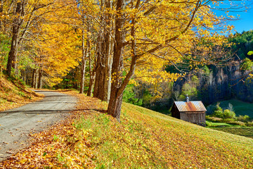 Dirt unpaved gravel road at autumn day in Vermont, USA.