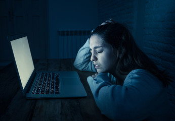 Scared woman on laptop in the dark feeling fear suffering online harassment and cyberbullying