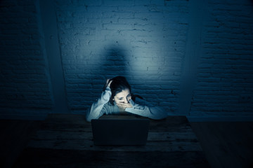 Scared woman on laptop in the dark feeling fear suffering online harassment and cyberbullying