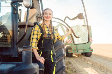 Bäuerin steht vor dem Traktor auf dem Kornfeld während der Ernte © Kzenon