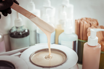 Skilled master mixing light wax in heating container