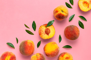 Flat lay composition with peaches. Ripe juicy peaches with green leaves on pink background. Flat...
