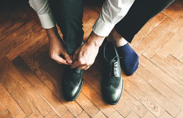 Groom is wearing the shoes. Stylish man getting clothed. Vintage style. Wedding day.