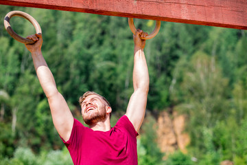 Fit man overcome obstacles using rings during extreme race in the boot camp