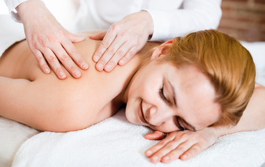 Obraz na płótnie Canvas Adult masseuse makes relaxing massage shoulder zone to young woman