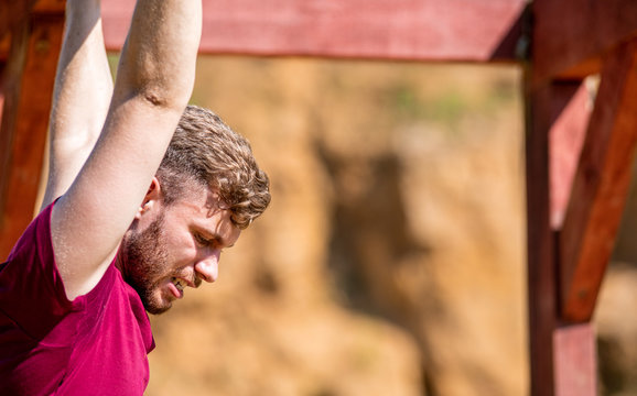Fit man overcome obstacles using rings during extreme race in the boot camp - Powered by Adobe