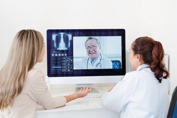 Fototapeta na wymiar Doctor and female patient getting consultation of experienced senior Asian orthopedic surgeon online