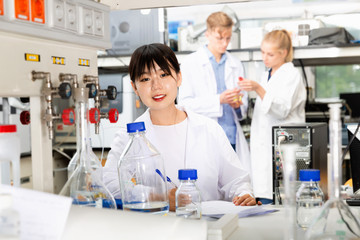 Young Chinese female student posing near equipment at laboratory