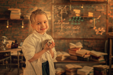 portrait of smiling girl in lab coat holding hedgehog