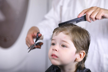 Hairdresser and boy. The boy is doing his hair. Cut hair child in the hairdresser.