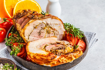 Classic Italian baked pork porchetta with oranges, copy space. Baked pork on white background. Italian cuisine concept.
