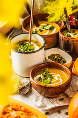 Autumn pumpkin soup puree with cream in cups, the autumn scenery. Healthy vegan food concept.