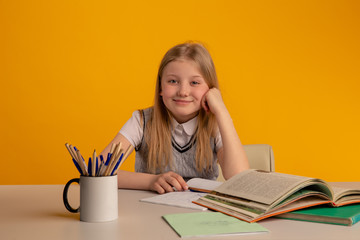 Happy child doing homework sitting isolated the bright yellow background