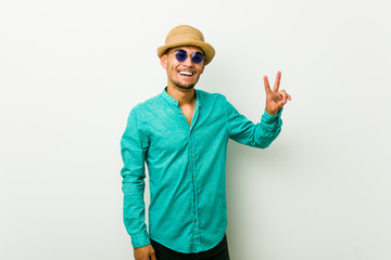 Young hispanic man wearing a summer clothes showing victory sign and smiling broadly.