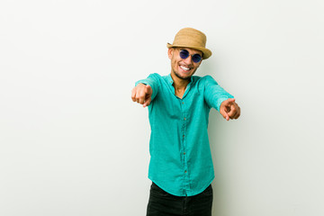 Young hispanic man wearing a summer clothes cheerful smiles pointing to front.