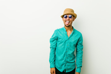 Young hispanic man wearing a summer clothes funny and friendly sticking out tongue.