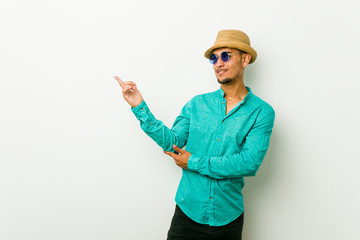 Young hispanic man wearing a summer clothes smiling cheerfully pointing with forefinger away.