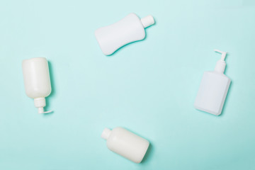 Set of White Cosmetic containers isolated on blue background, top view with copy space. Group of plastic bodycare bottle containers with empty space for you design