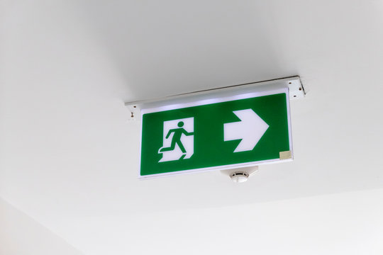 Fire exit sign. Emergency fire exit door exit door on ceiling. Green emergency exit sign showing the way.