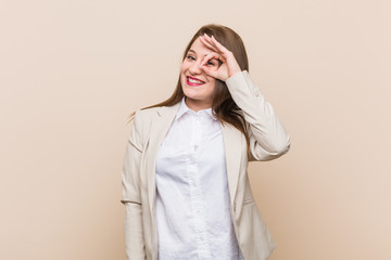 Young business woman excited keeping ok gesture on eye.