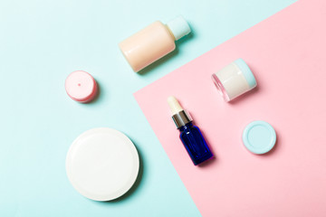 Top view of cosmetic containers, sprays, jars and bottles on pink background. Close-up view with empty space for your design