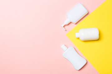Set of White Cosmetic containers isolated on yellow background, top view with copy space. Group of plastic bodycare bottle containers with empty space for you design