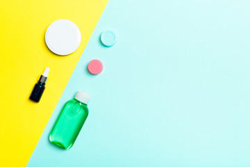 Top view of cosmetic containers, sprays, jars and bottles on yellow and blue background. Close-up view with empty space for your design