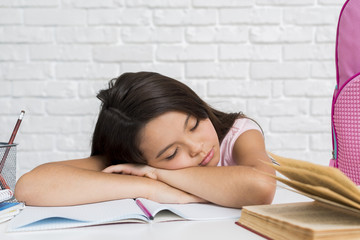 Schoolgirl asleep with head on copybook