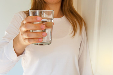 A woman holding a glass of water to drink. Drinking water is beneficial to the body. Good health...