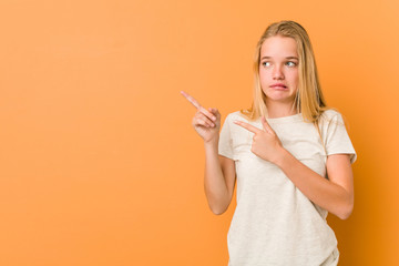 Cute and natural teenager woman shocked pointing with index fingers to a copy space.