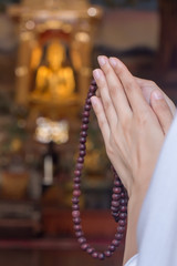 Religious Asian buddhist woman praying, chanting mantra to the lord Buddha with buddhist style rosary beads in hand