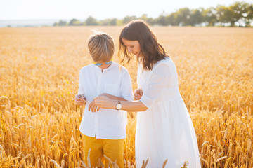 Photo of mother showing something to his son, in a wheat field