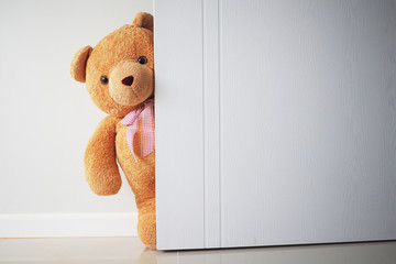 Teddy bear with brown hair behind open door. Background for kids play Teddy bear