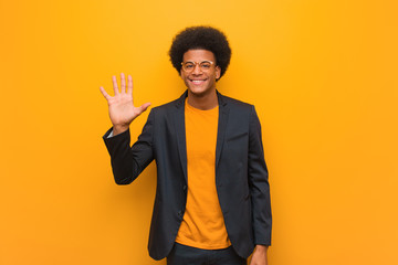 Young business african american man over an orange wall showing number five