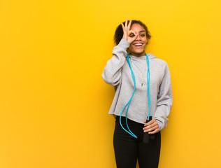 Young fitness black woman confident doing ok gesture on eye. Holding a jump rope.