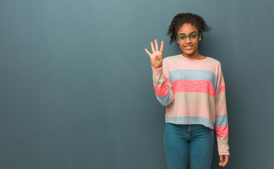 Young african american girl with blue eyes showing number four